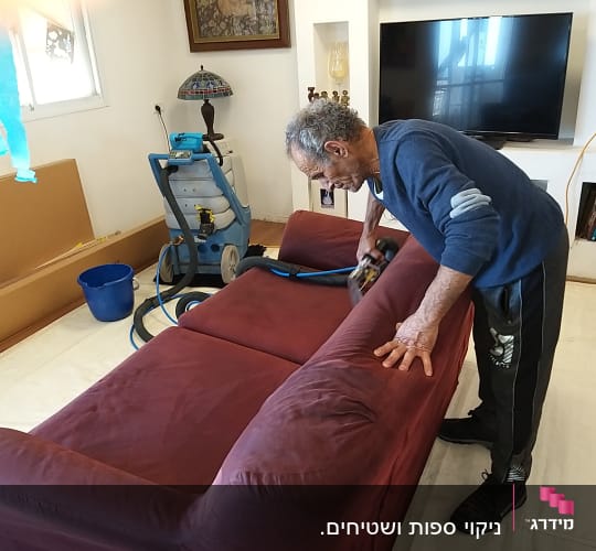 אדם מנקה ספה עם מכונת ניקוי וציוד מקצועי